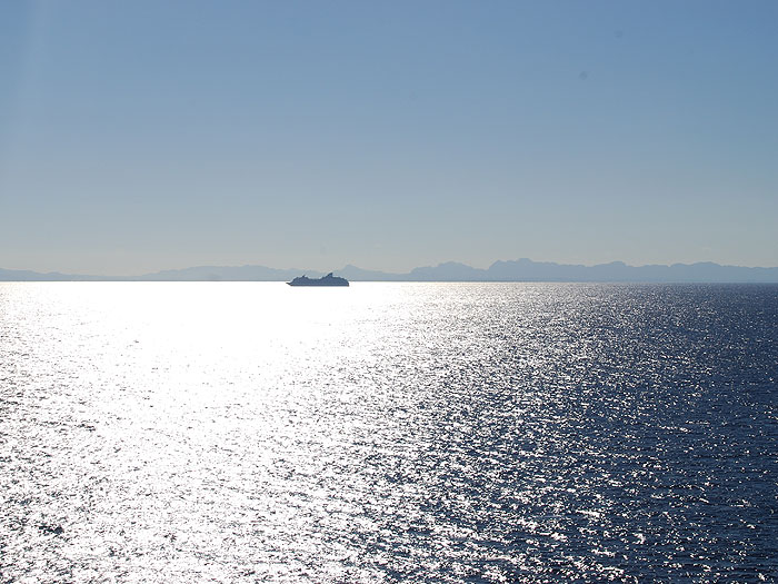 Close-up of a cruise ship siloetted in front of the mountainous coast of Belize - Ben Kitzmiller